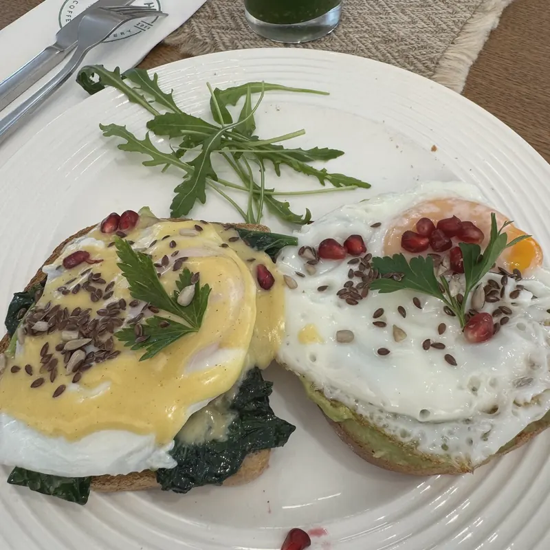 Vegetarian eggs Benedict on spinach with hollandaise and seeds