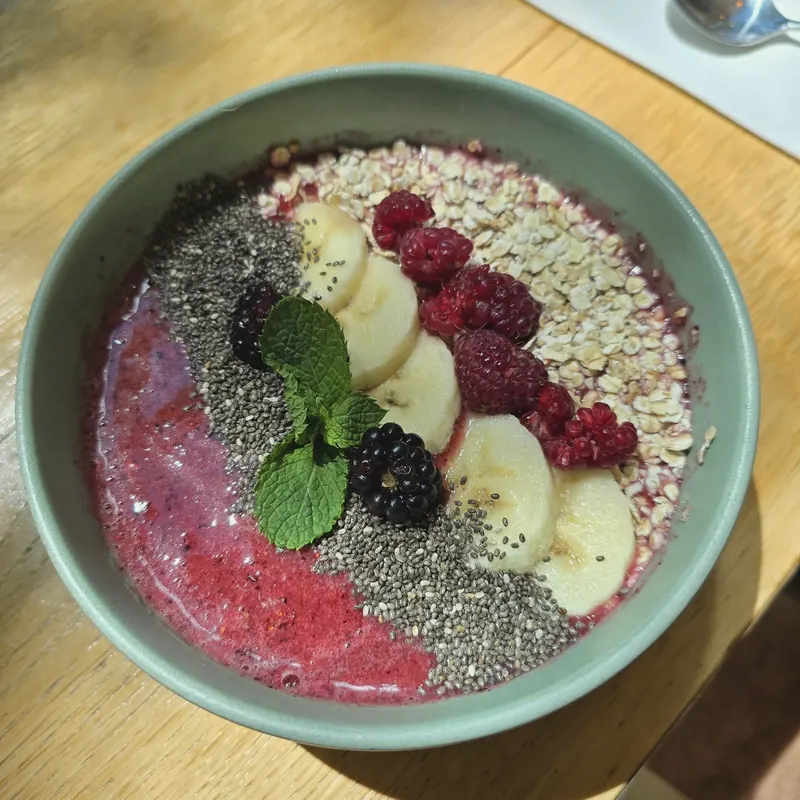 Berry smoothie bowl topped with banana, raspberries, blackberries, chia, oats and mint