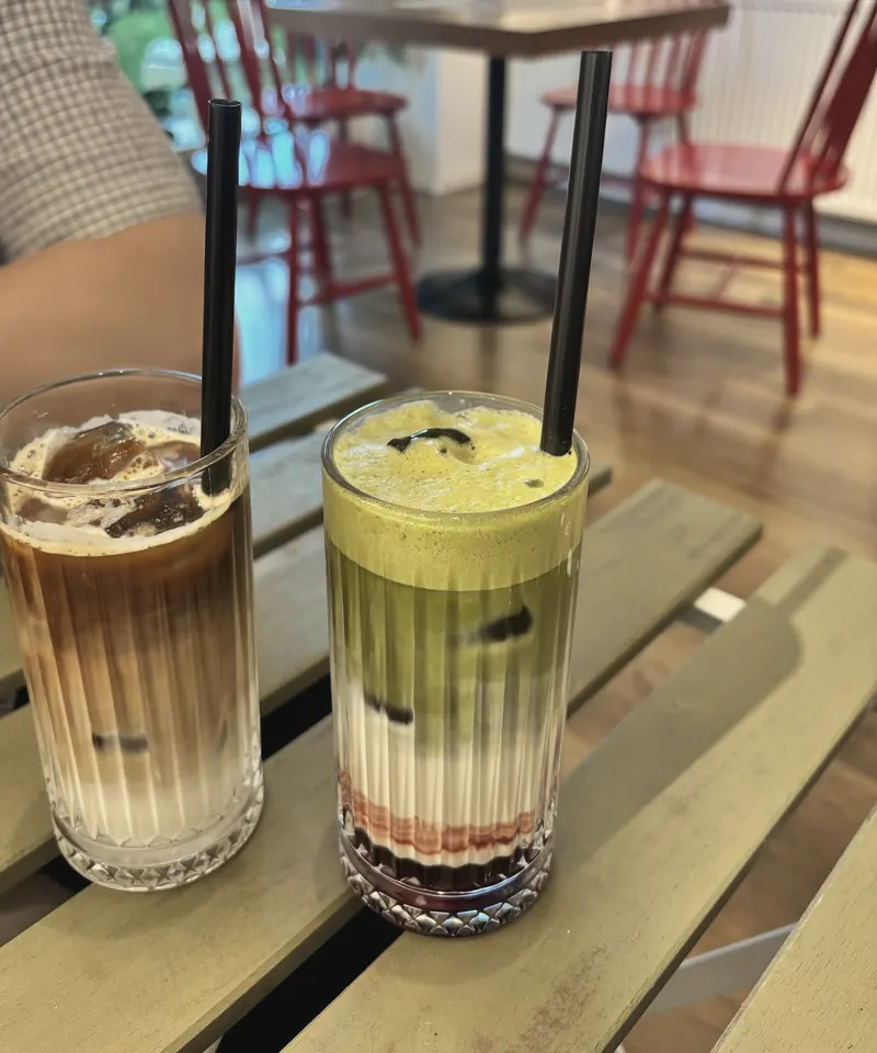 An iced coffee and an iced matcha latte on a wooden table